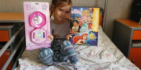 Powiększ grafikę: Dziewczynka trzyma prezenty z okazji Dnia Chorego